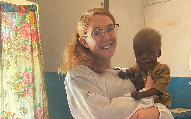 澳门新普京注册 alumna and Peace Corps volunteer Mackenzie Hafer with a child in a Madagascar health clinic