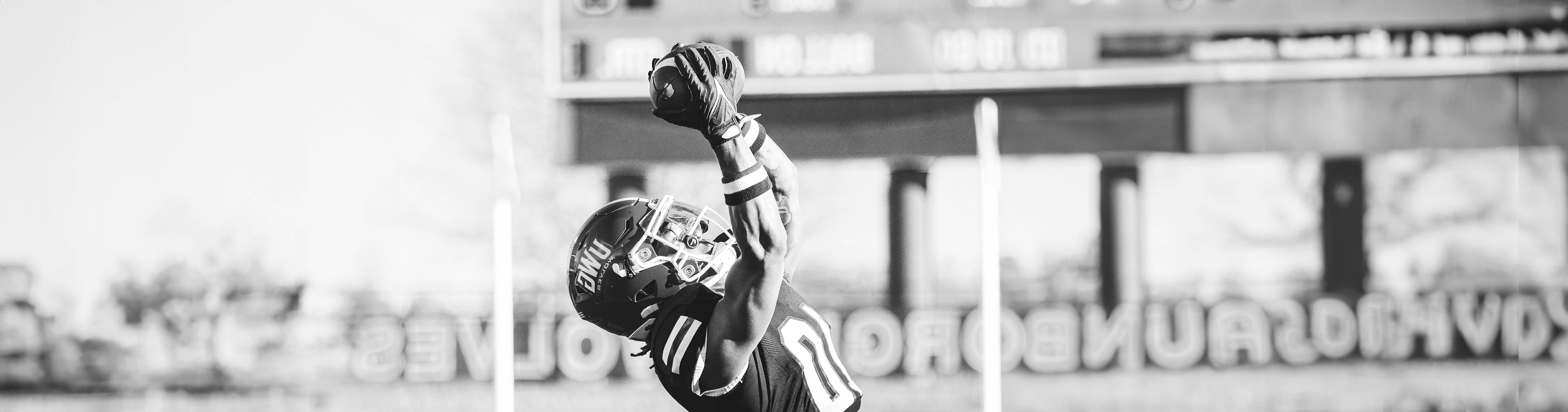 Black and white football player catching ball in the air.